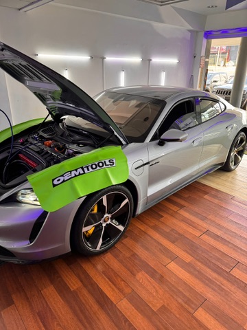 Porsche Taycan eléctrico en servicio de A/C con personal y herramientas OEM en taller.